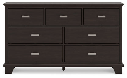 Dark wooden dresser with four large and three small drawers, featuring silver handles.