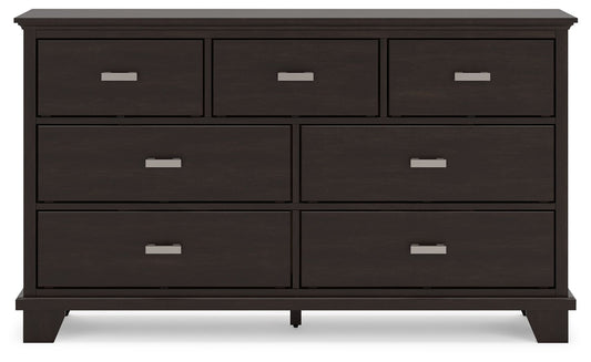 Dark wooden dresser with four large and three small drawers, featuring silver handles.