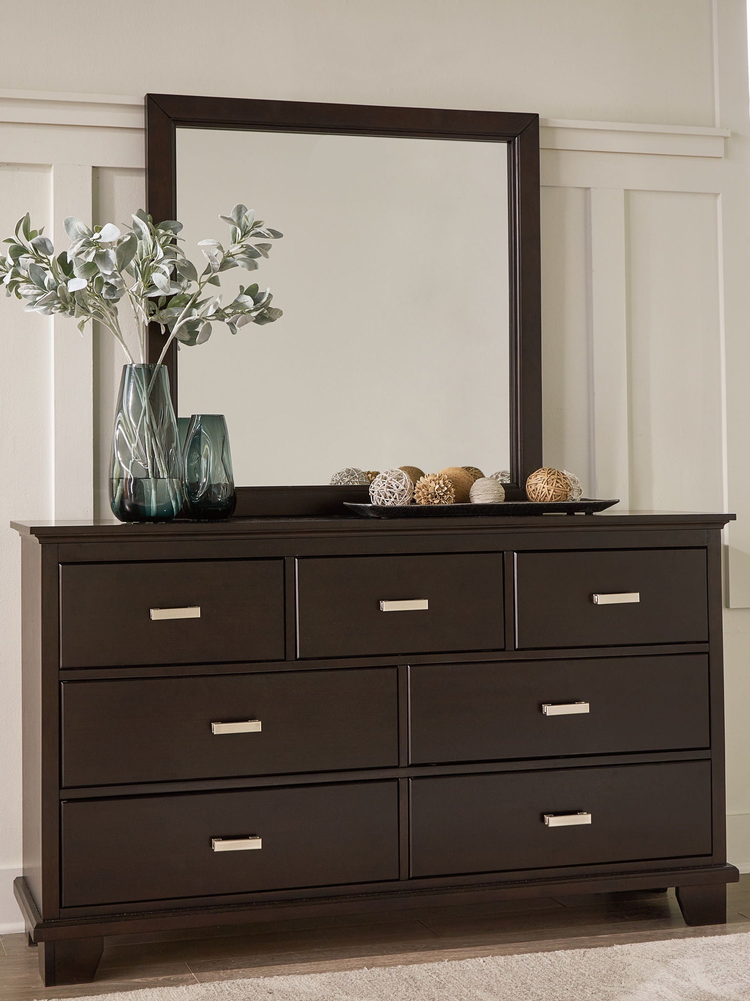 Dark wood dresser with a mirror, potted greenery, and decorative bowl on top.